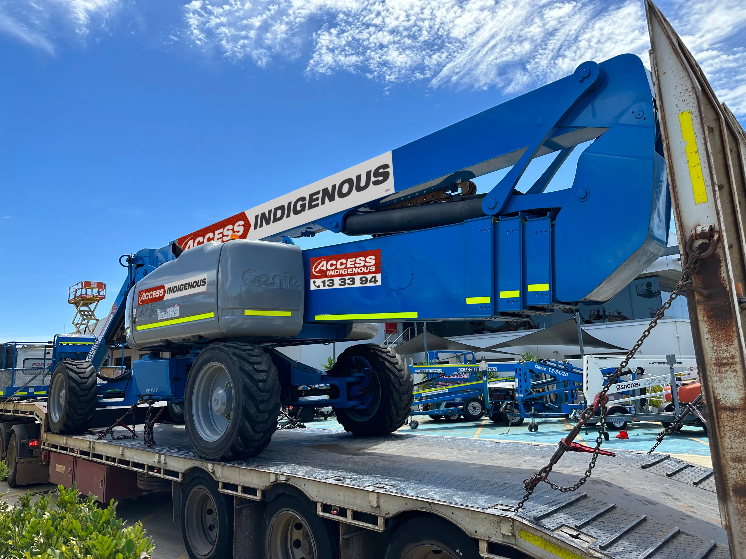 Access Indigenous boom lift loaded on transport truck at equipment depot
