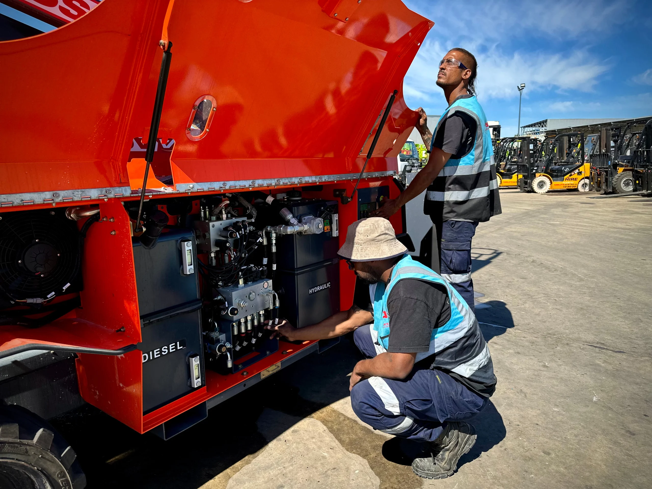 Technicians servicing Access Hire diesel generator at equipment yard